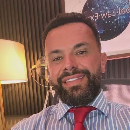 Legal professional smiling at desk with a globe and legal-themed decor in modern office setting.