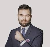 Lawyer in business suit adjusting cufflink against a neutral background.