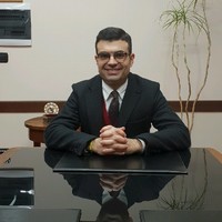 Attorney seated at desk with hands clasped, in a law office setting.