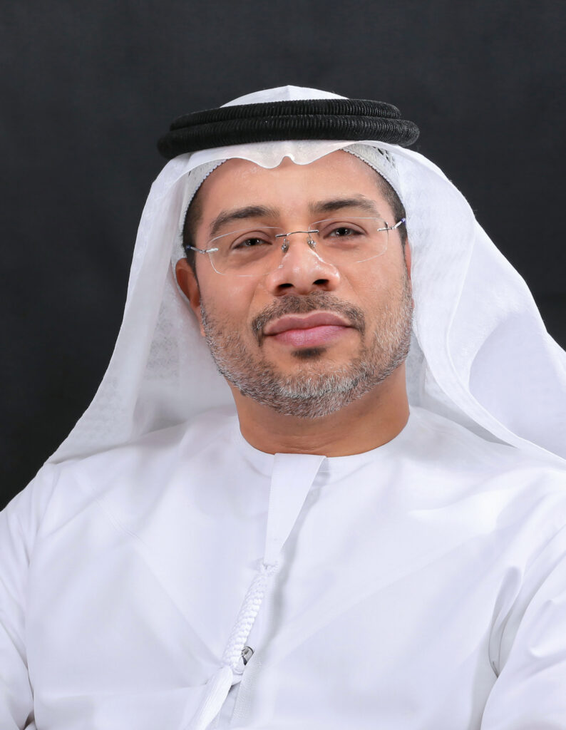 Lawyer wearing traditional attire, smiling against a dark background.