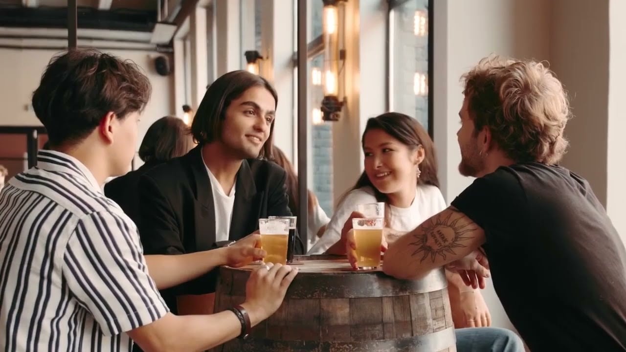 Group of four individuals socializing at a table, enjoying drinks in a casual setting.