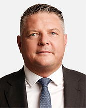 Lawyer in a suit, facing the camera, with a neutral expression and professional appearance.