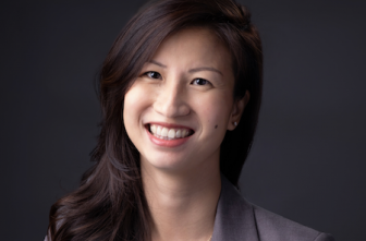 Attorney smiling warmly for a professional headshot against a neutral backdrop.