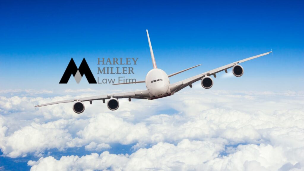 Airplane flying through clouds with Harley Miller Law Firm logo in the sky.