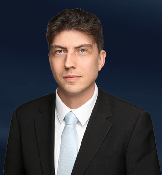 Lawyer in a suit with a light blue tie, posed against a dark background.