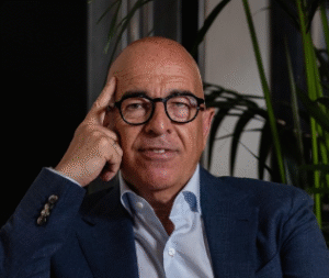 Professional man with glasses thoughtfully posing in a modern office setting with indoor plants.
