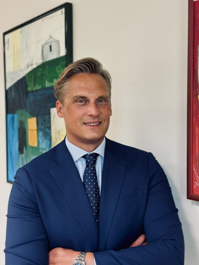 Lawyer in professional attire smiling in an office with abstract art in the background.