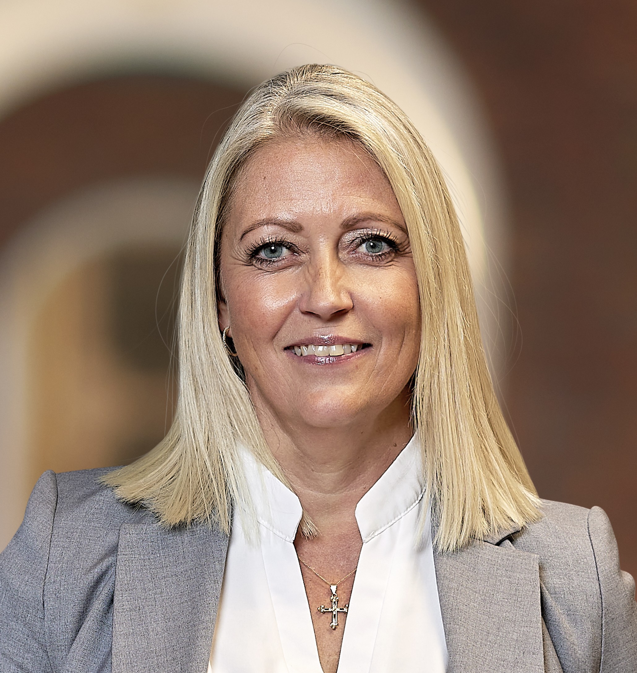 Female attorney posing confidently in a professional setting, wearing a business suit and smiling.