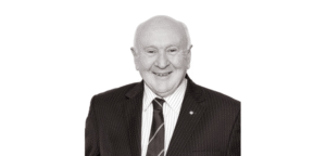 Senior legal professional smiling in formal attire, likely in a law office setting.