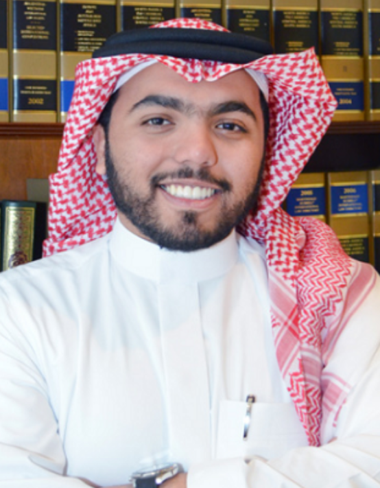 Lawyer smiling confidently with arms crossed in front of legal books in a law office setting.