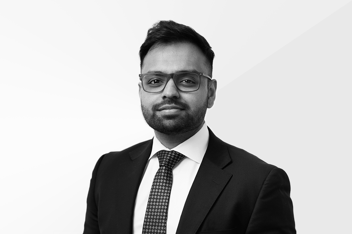 Lawyer in a suit with glasses, posing against a neutral background.