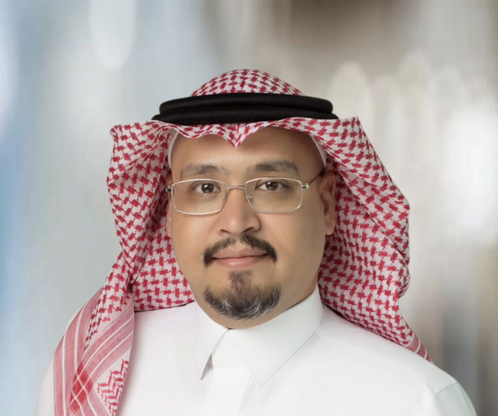 Legal professional wearing traditional attire, smiling against a neutral background.