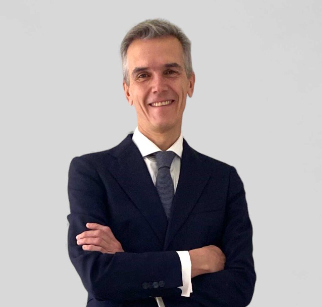 Smiling lawyer in a suit with arms crossed against a neutral background.