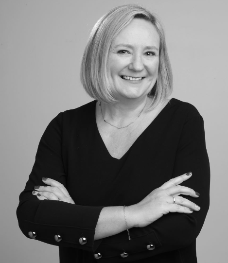 Female lawyer smiling and standing with arms crossed, dressed in professional attire against a neutral background.