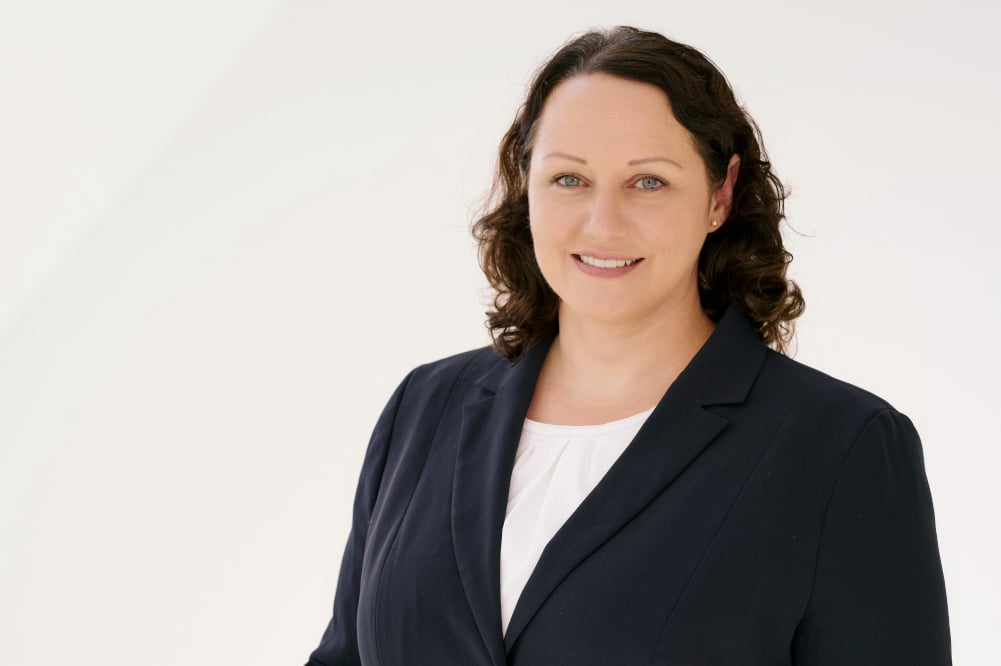 Legal professional in a suit, smiling against a neutral background, showcasing approachability in a legal setting.
