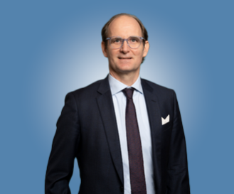 Lawyer in suit standing against a blue background, presenting a professional demeanor.