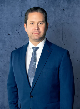 Attorney in a business suit standing confidently against a textured background.
