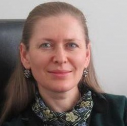 Attorney with long hair and earrings, seated at a desk in a professional setting.