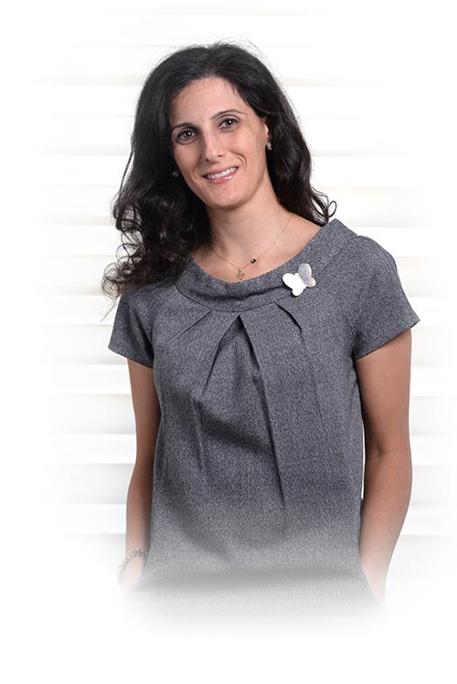 Legal professional standing confidently, wearing a gray blouse, with a subtle smile against a neutral background.