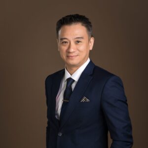 Lawyer in a dark suit with a patterned tie, posing confidently against a neutral background.