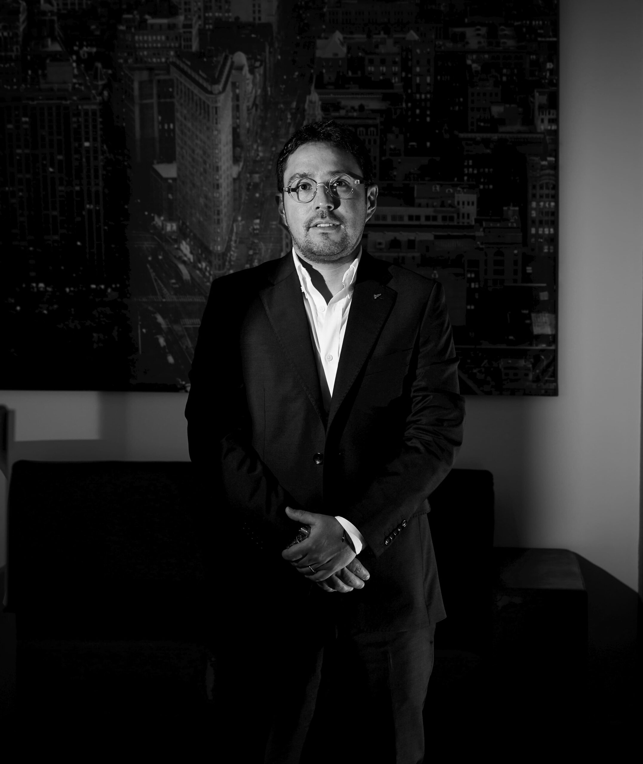 Lawyer standing confidently in a darkened office, with a cityscape backdrop.