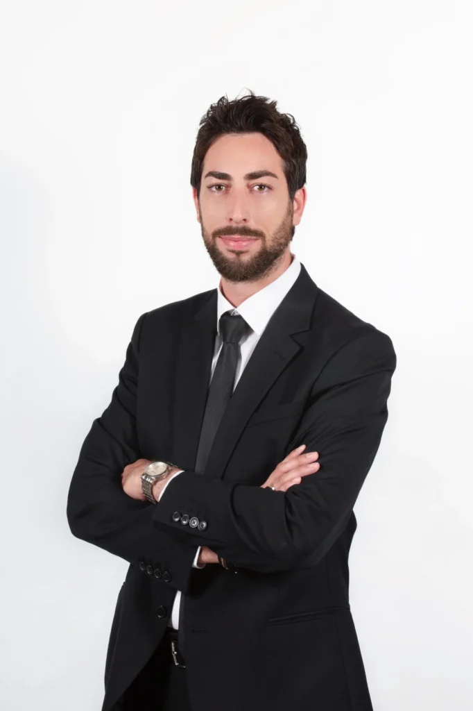 Attorney in a suit with arms crossed, posing against a plain white background.