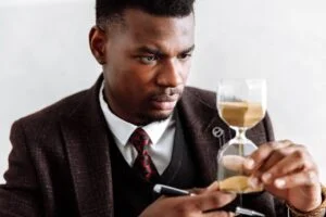 Lawyer examining hourglass while contemplating time management in a professional setting.