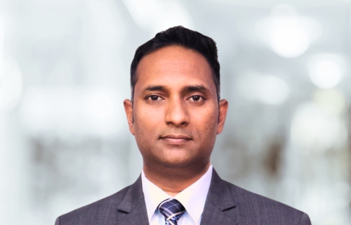 Lawyer in a professional suit, looking directly at the camera in a blurred office setting.