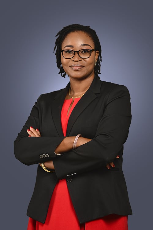 Attorney standing confidently with arms crossed, wearing a black blazer over a red top against a neutral background.