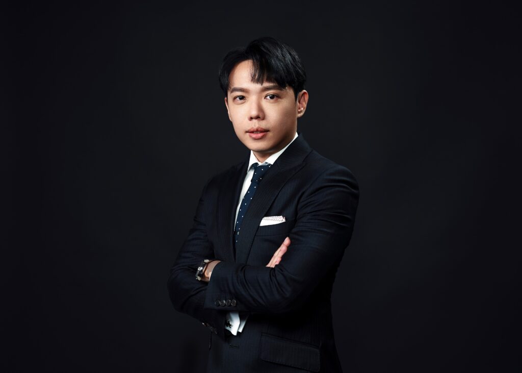 Attorney in formal suit standing confidently with arms crossed against a dark backdrop.