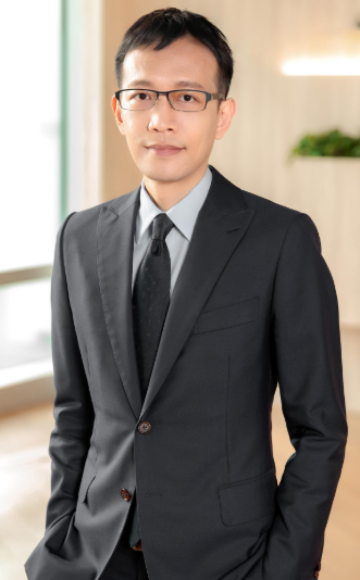 Lawyer in a suit and glasses, standing in a modern office environment with natural light.