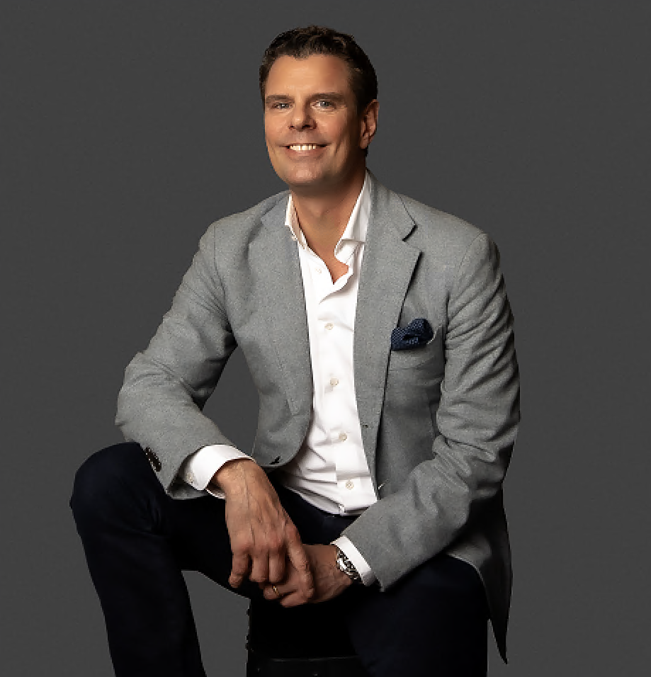 Lawyer seated confidently, wearing a suit, against a neutral background.