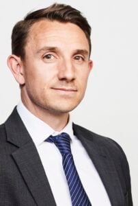 Attorney posing for a professional portrait, wearing a suit and tie with neutral background.