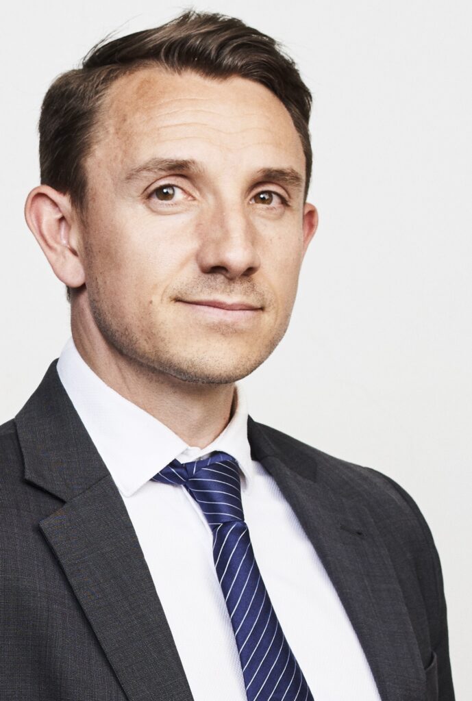 Attorney posing for a professional portrait, wearing a suit and tie with neutral background.