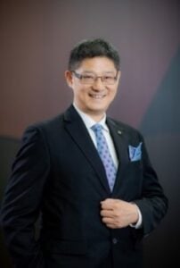 Lawyer in a suit smiling confidently, posing for a professional portrait against a geometric background.