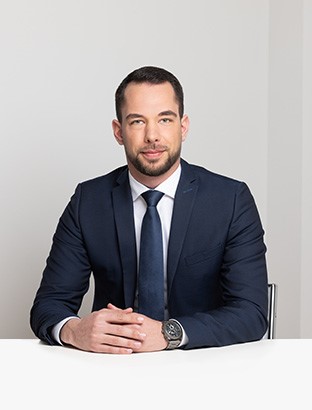 Lawyer seated at a desk, hands clasped, in a professional office setting.