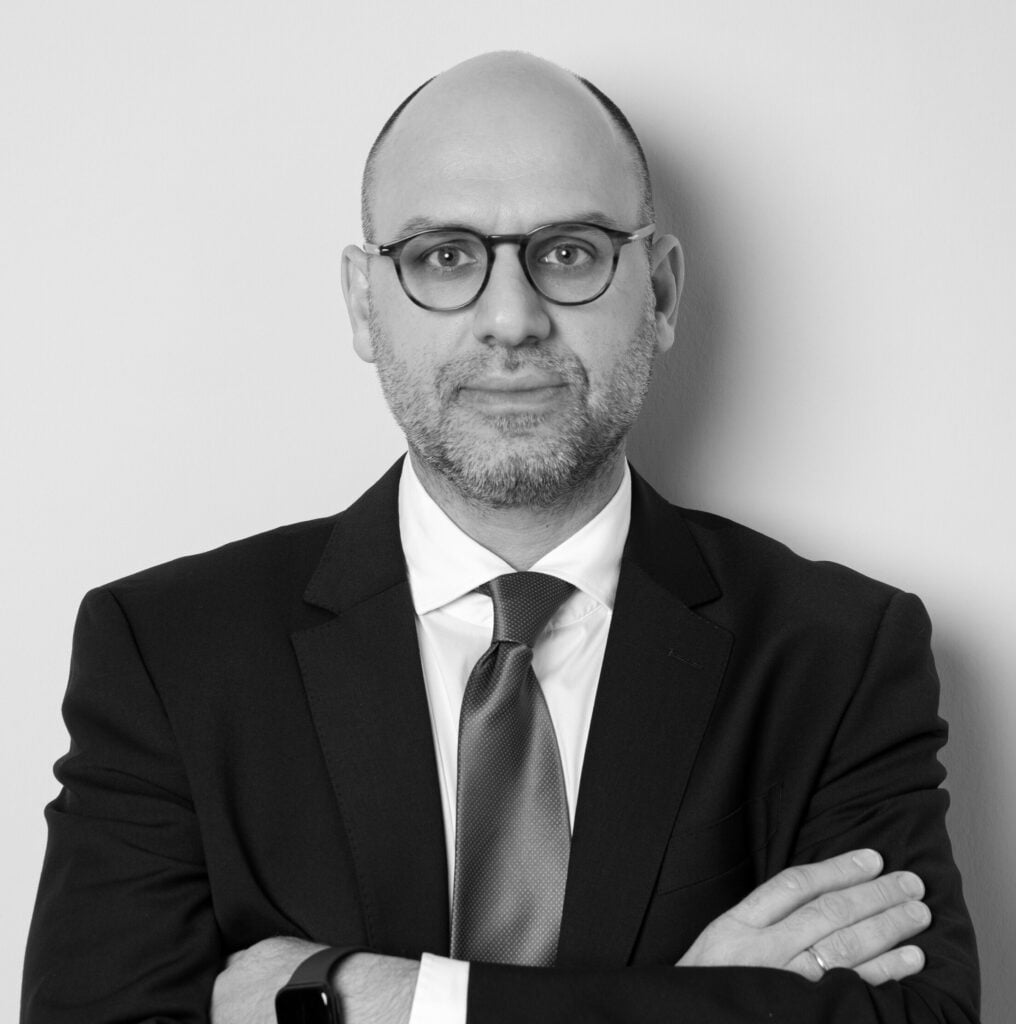 Attorney posing confidently with arms crossed against a neutral background.