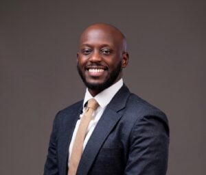 Smiling lawyer in a suit against a neutral backdrop, professional appearance, ready for client consultations.