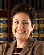 Attorney smiling in front of legal books in an office setting.