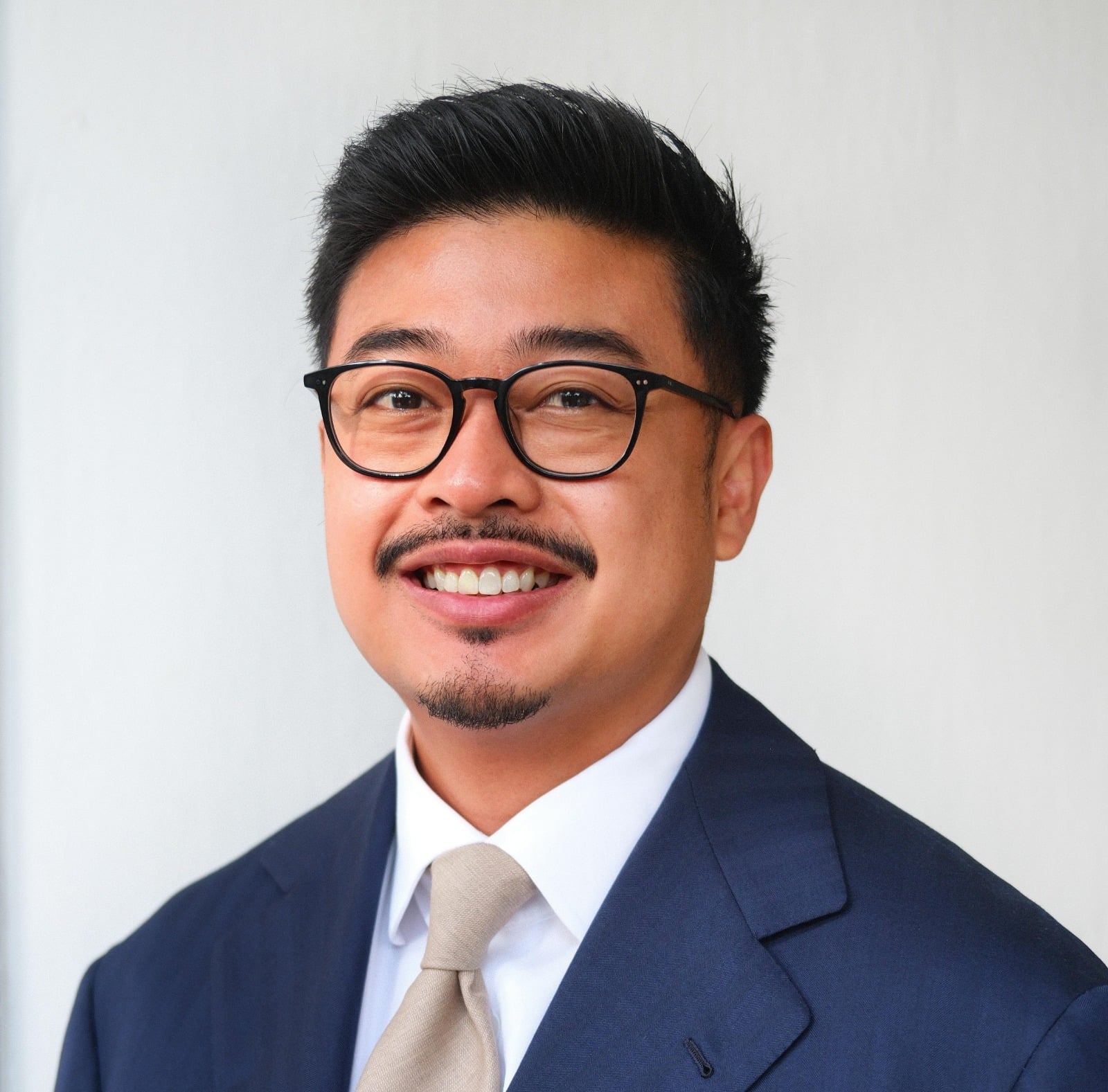 Lawyer in a suit smiling, posed against a neutral background, suitable for professional profile or directory.
