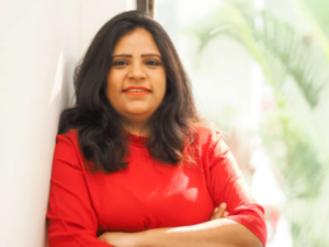 Legal professional standing with arms crossed, dressed in a red top, in a bright office environment.
