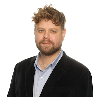 Lawyer with curly hair wearing a black blazer, posing for a professional headshot against a white background.