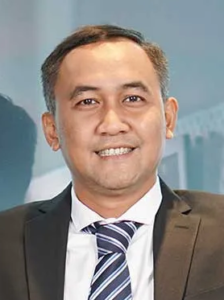 Lawyer smiling confidently, wearing a suit and tie, in a professional office setting.