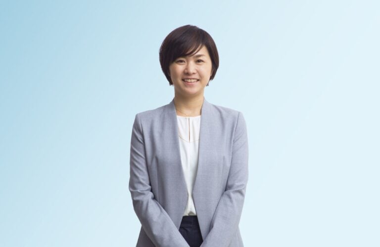 Attorney standing confidently, wearing a grey blazer, with a neutral background.