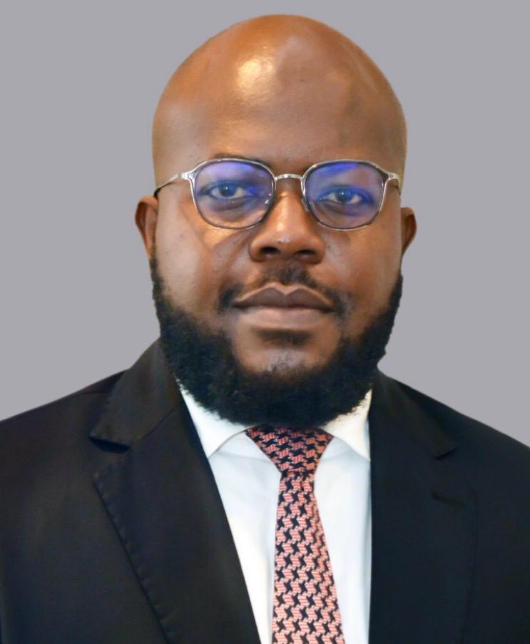 Attorney in a suit with a tie, gazing forward against a neutral background.
