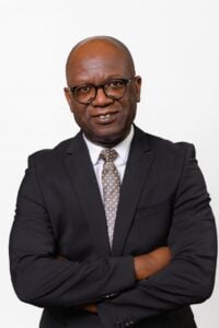 Lawyer posing confidently with arms crossed in professional attire against a plain background.