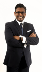 Attorney smiling with arms crossed, wearing a suit against a plain background.