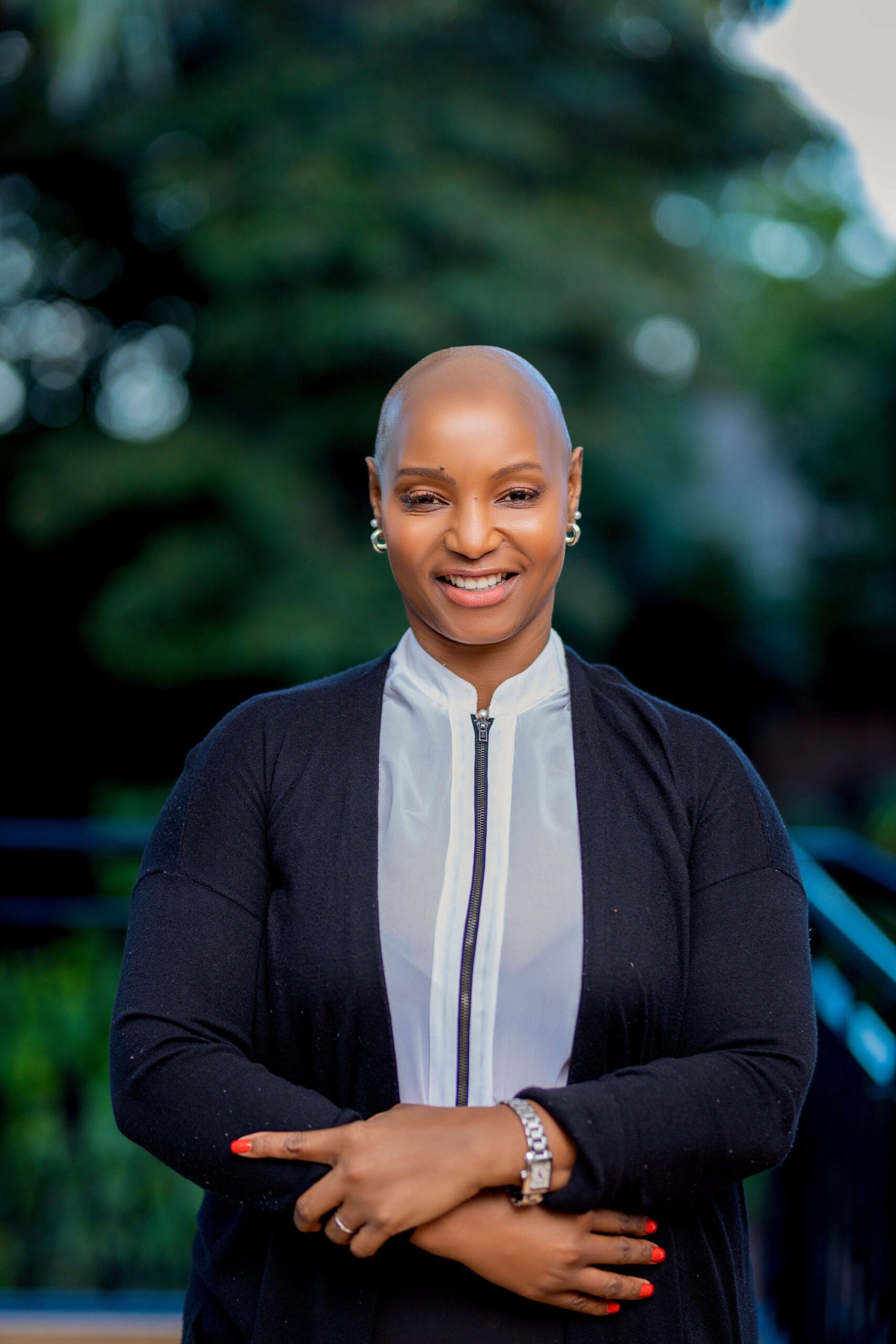 Legal professional smiling with arms crossed, set against a green outdoor background.