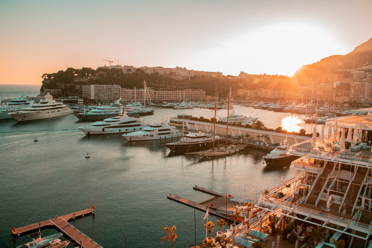 Marina view at sunset with multiple luxury yachts and modern buildings in coastal setting.