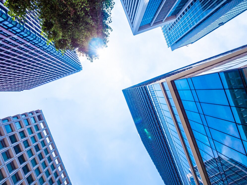 Modern skyscrapers viewed from ground level, showcasing reflective glass facades and city architecture.